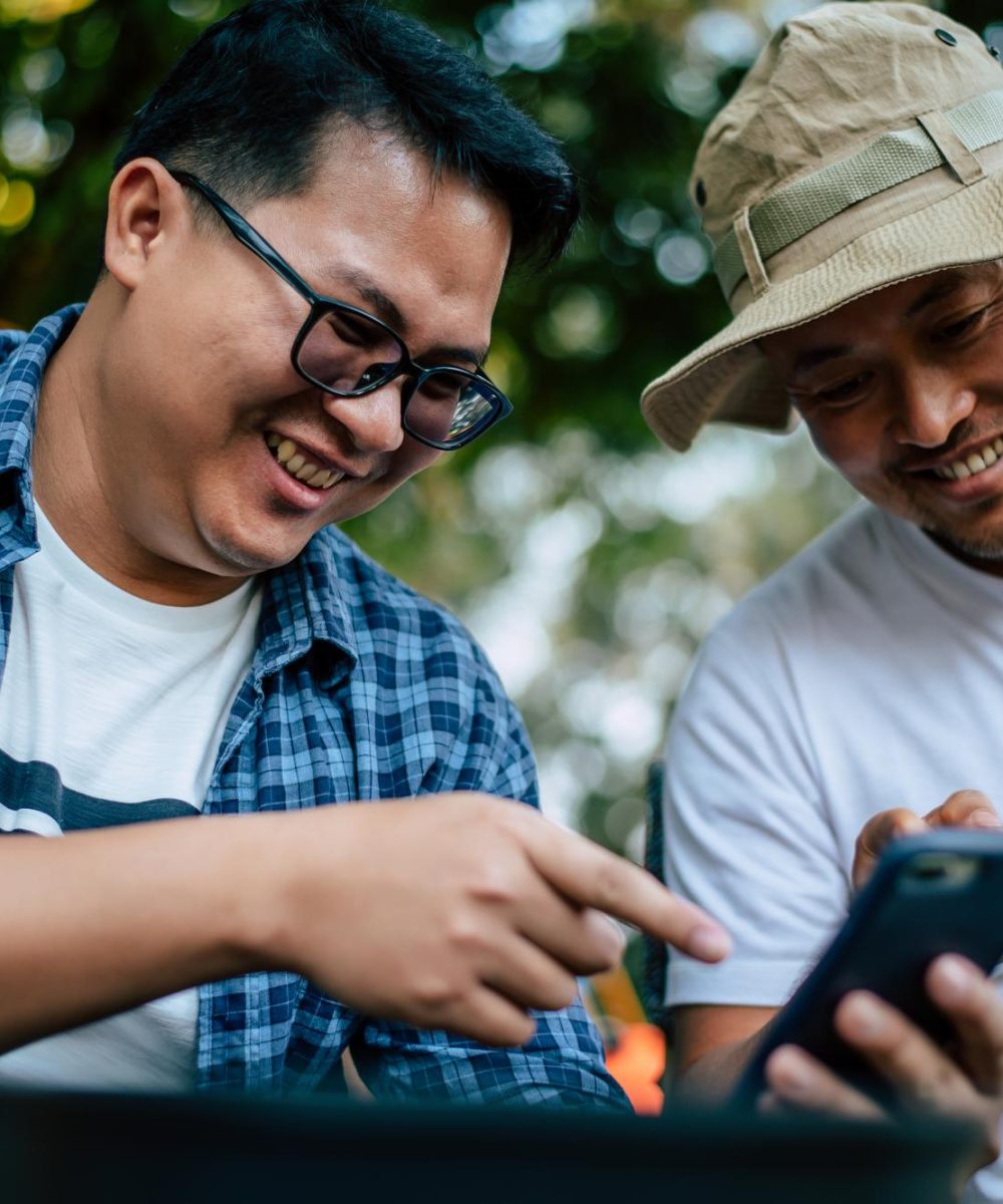 happy-asian-man-friend-sitting-holding-phone